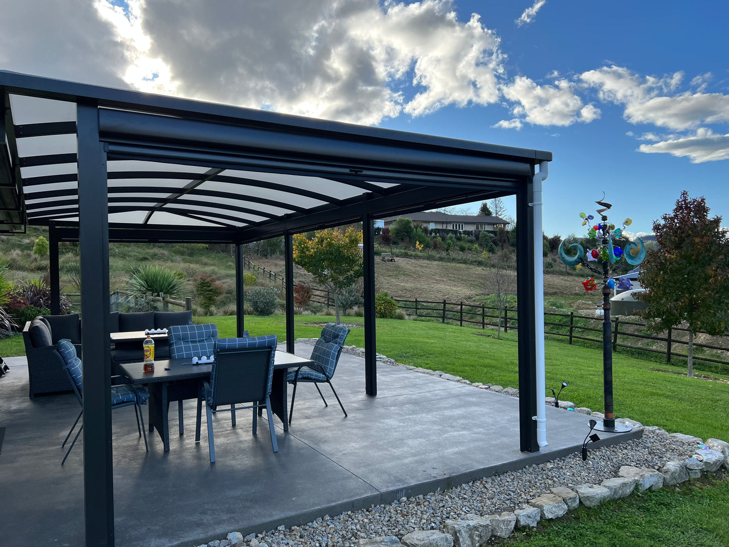 Patio with black pergola, outdoor furniture, and scenic background