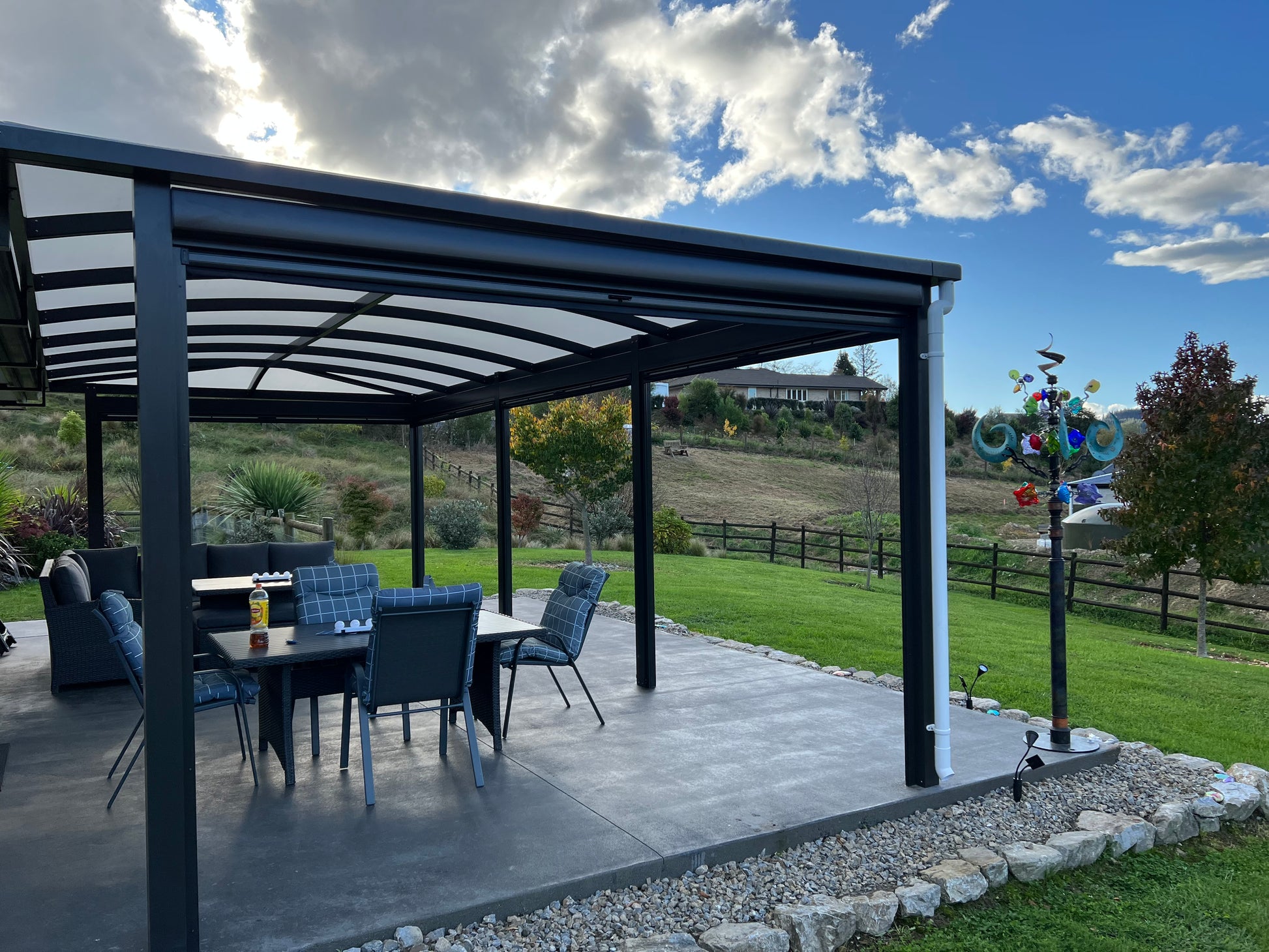 Patio with black pergola, outdoor furniture, and scenic background